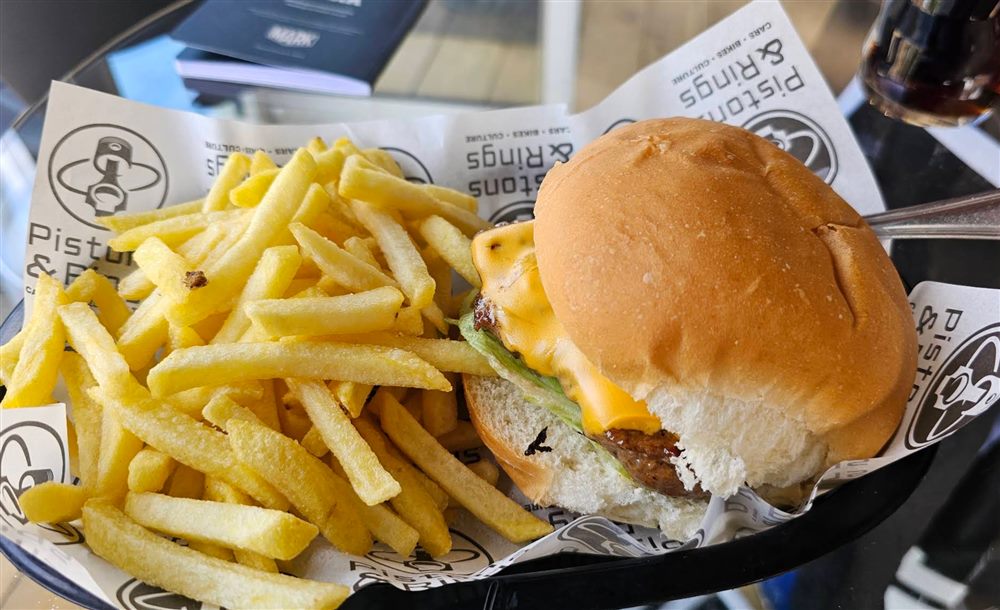 A burger and chips served in Pistons & Rings branded packaging
