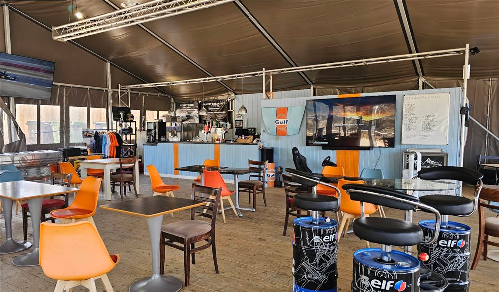Inside the Pistons & Rings clubhouse, with motorsport-themed seating and a racing sim in the corner